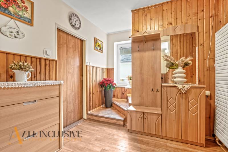 Ein Flur in einem Einfamilienhaus mit Holzverkleidung, Dekorationen und einem Boden mit Holzdekor.