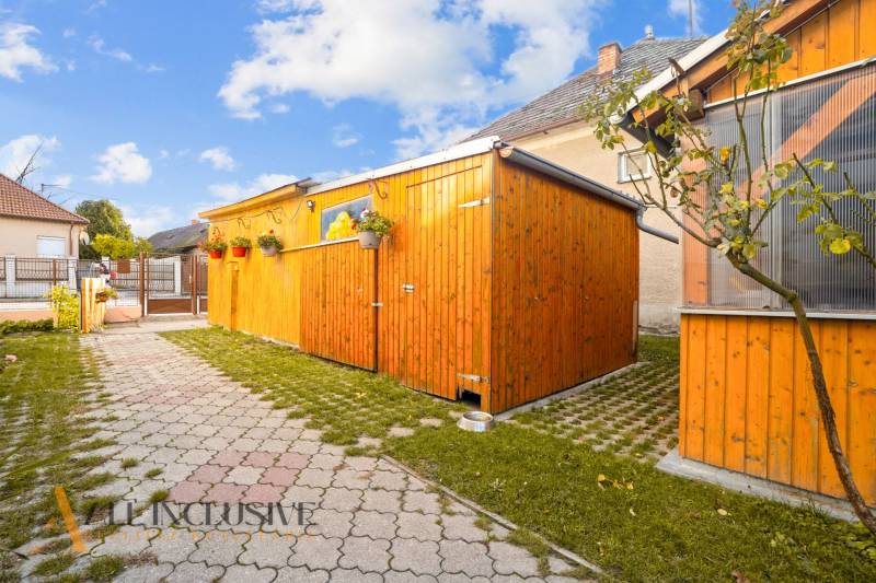 Der Hof des Einfamilienhauses in Dunajská Streda mit einem Holzunterstand und einem gepflasterten Weg.