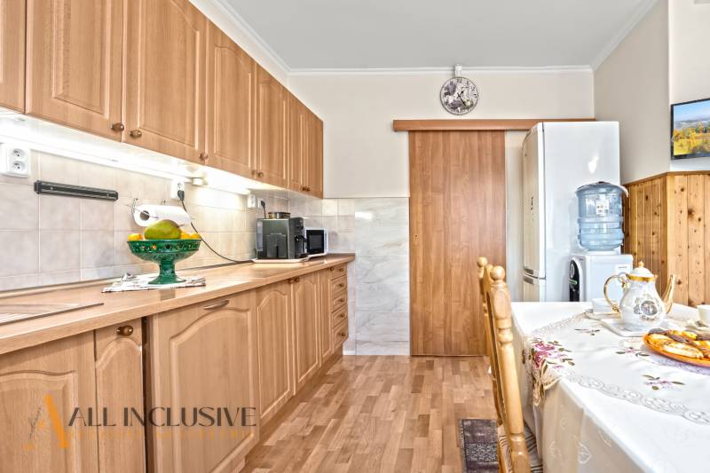 Eine Küche in einem Einfamilienhaus mit einem Boden in Holzoptik und Holzmöbeln.