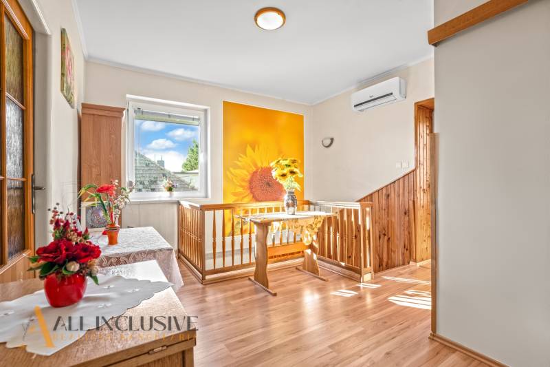 Ein Einfamilienhaus mit einer Wand mit Sonnendekor, einem Boden mit Holzdekor und einer Vase mit Blumen.