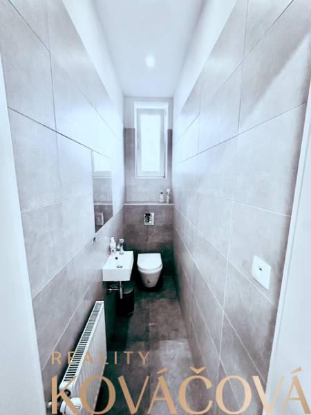 Schmales WC mit Fenster, Waschbecken und Keramikfliesen. Büros Reality Kováčová.