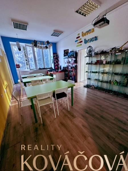 Innenraum eines Büros mit Holzboden und Tischen, Regale mit Brick-Spielzeug.