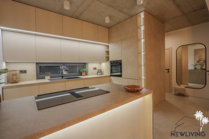 Küche in einem Einfamilienhaus mit eingebauten Geräten, Arbeitsplatten und einem Bodenbelag in Holzoptik.