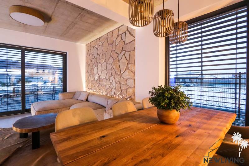 Innenraum eines Einfamilienhauses mit einer Steinwand, einem bequemen Sofa und einem Boden mit Holzdekor.