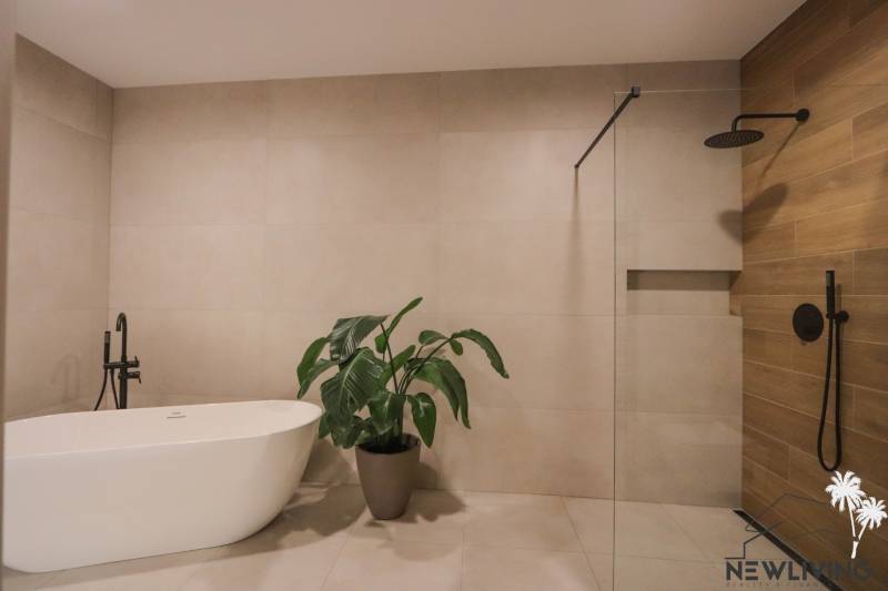 Badezimmer in einem Einfamilienhaus mit Badewanne, Pflanze, Dusche und Fliesen.