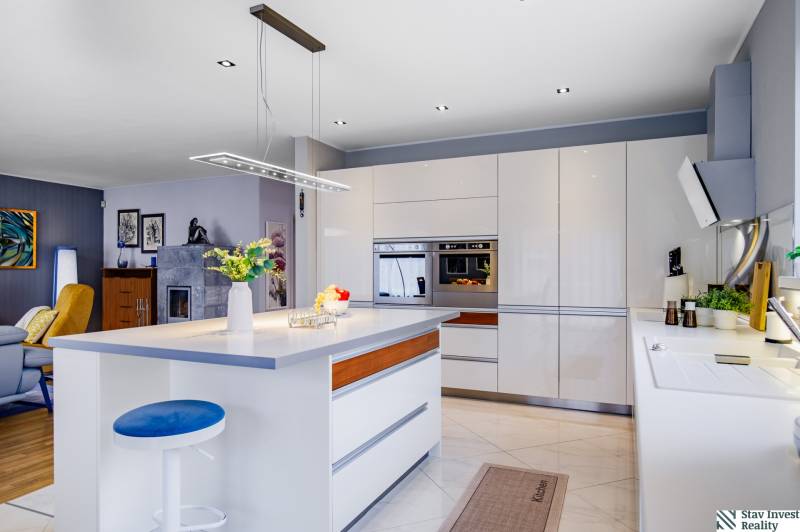 Küche in einem Einfamilienhaus mit Insel, Leuchte, eingebautem Ofen und Zubehör.