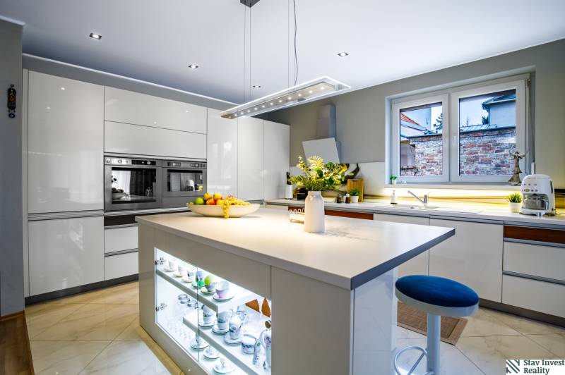 Küche in einem Einfamilienhaus mit zentraler Insel, weißen Schränken und Geräten.