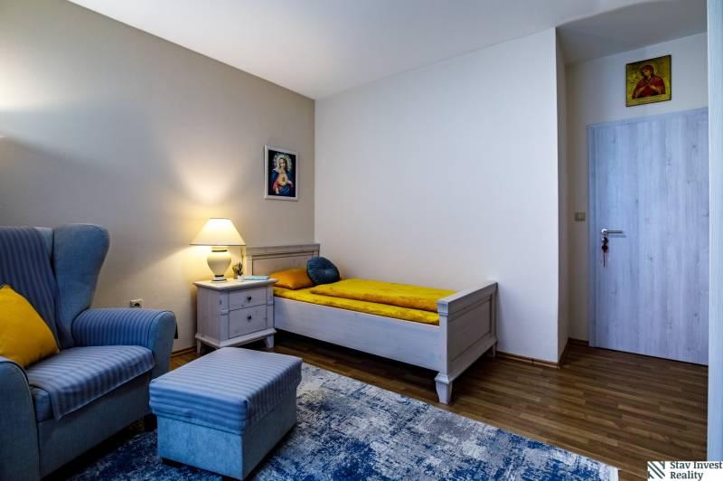 Ein Zimmer im Familienhaus mit einem Sessel, einem Bett, einem Nachttisch und einem Boden mit Holzdekor.