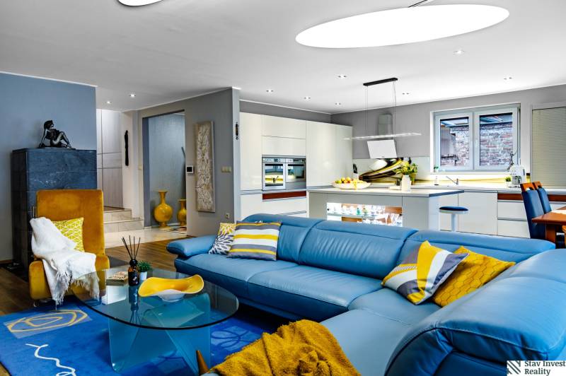 Wohnzimmer in einem Einfamilienhaus mit blauer Couch und Küche, Holzboden.