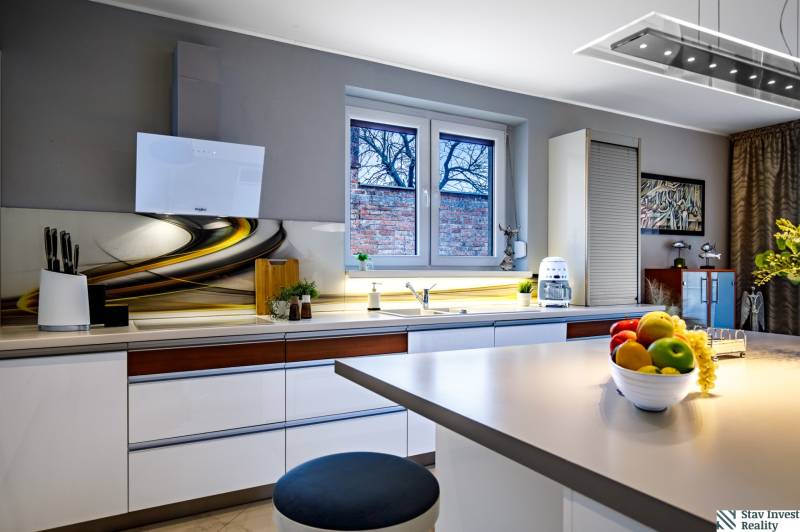 Küche im Einfamilienhaus mit stilvoller Arbeitsplatte, weißen Schränken und Dekorationen am Fenster.