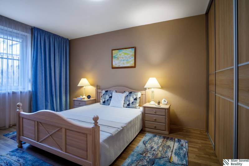 Schlafzimmer im Einfamilienhaus mit Bett, Nachttischen und Boden in Holzoptik.