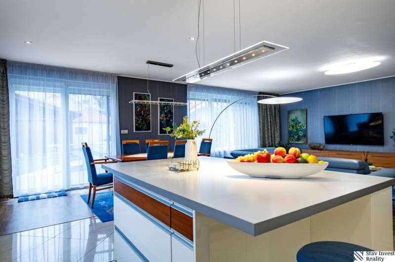 Wohnzimmer in einem Einfamilienhaus mit Kücheninsel, Sofa und Esstisch.