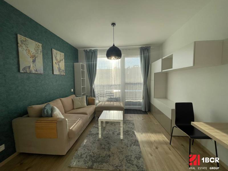 Wohnzimmer einer Einzimmerwohnung mit Sofa, Hirschdekoration und Holzboden.