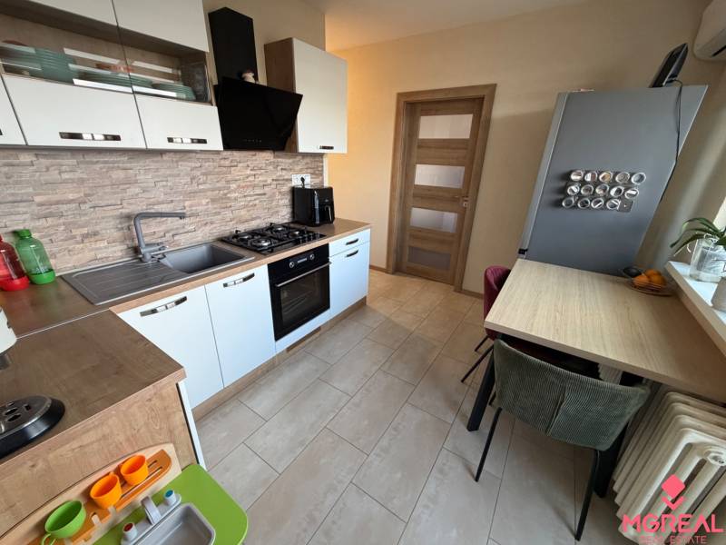 Küche in einer 4-Zimmer-Wohnung mit Holzboden und eingebauten Geräten.