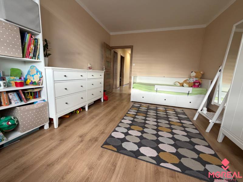 Kinderzimmer mit Bett, Teppich und Boden mit Holzdekor in einer 4-Zimmer-Wohnung.