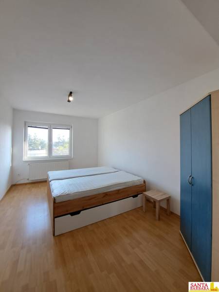 Schlafzimmer in einer 4-Zimmer-Wohnung mit Bett, Schrank und Boden in Holzoptik.