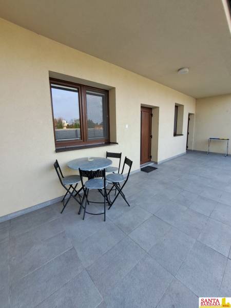 Eine Terrasse mit Sitzgelegenheiten in einer 4-Zimmer-Wohnung mit gefliestem Boden und hellen Wänden.