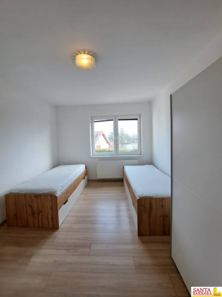 Ein Zimmer in einer 4-Zimmer-Wohnung mit zwei Betten und einem Boden in Holzoptik.