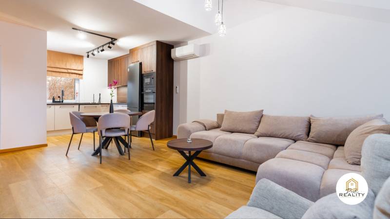 Wohnzimmer in einer Einzimmerwohnung mit Küche, Sofa und Holzboden.