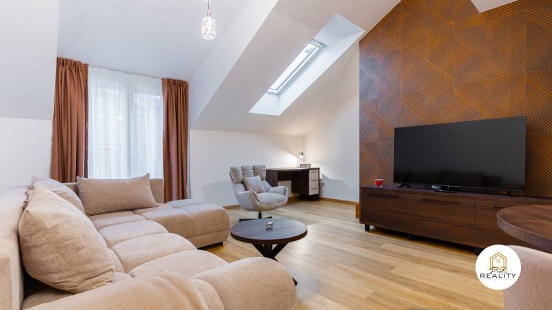 Helles Wohnzimmer in einer Einzimmerwohnung mit Holzboden und Dachfenster.