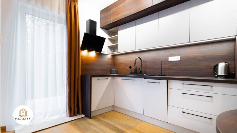 Küche in einer Einzimmerwohnung mit Holzboden, Vorhang und modernen Geräten.