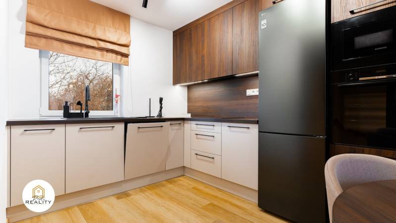 Küche in einer Einzimmerwohnung mit Holzboden und modernen Geräten.