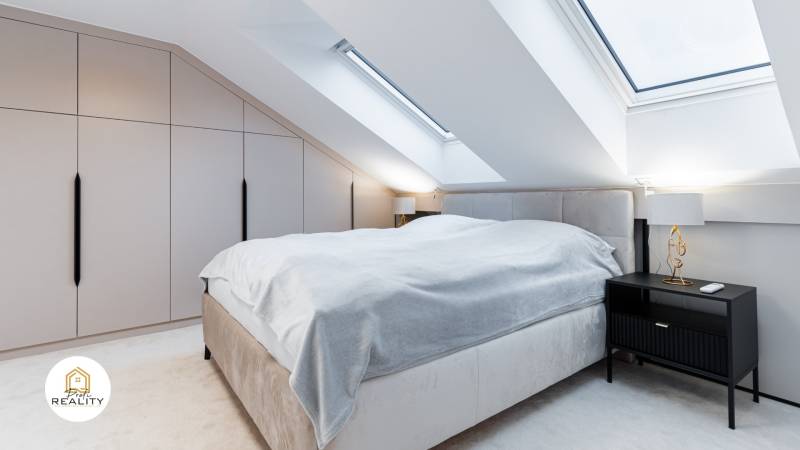 Ein Schlafzimmer im Dachgeschoss mit einem großen Bett, einem Nachttisch und einem Einbauschrank.