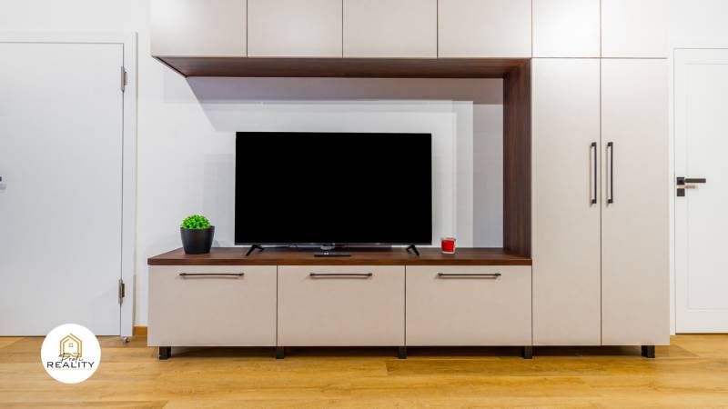 Wohnwand in einer Einzimmerwohnung, Boden mit Holzdekor, Fernseher und Dekorationen.