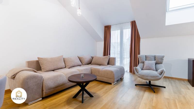Helles Wohnzimmer mit Sofa, Sessel und Holzboden in einer Einzimmerwohnung.