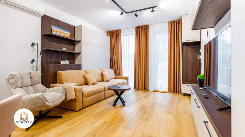 Wohnzimmer mit Sofa, Sessel und Holzboden in einer Einzimmerwohnung.