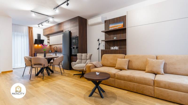 Innenraum einer Einzimmerwohnung mit hellem Boden in Holzoptik und gemütlicher Sitzecke.