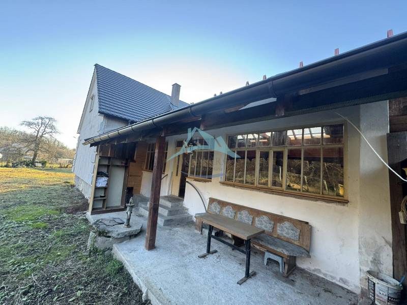 Ein Einfamilienhaus in Demandice mit Garten, Holzbänken und einem Außenbereich zum Sitzen.