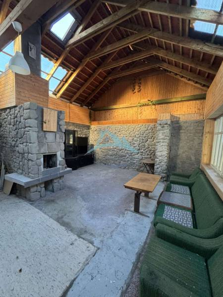 Innenraum eines Einfamilienhauses mit Steinkamin und Holzverkleidung.