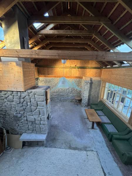 Steinwände, Holzdecke und Sitzgelegenheiten in einem Einfamilienhaus.