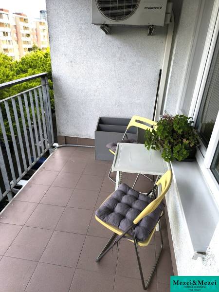 Balkon einer 2-Zimmer-Wohnung in Bratislava mit Stühlen und Grünpflanzen, geeignet zum Entspannen.