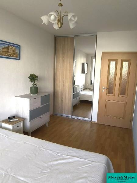 Schlafzimmer in einer 2-Zimmer-Wohnung mit Holzboden, Einbauschrank und Kommode.