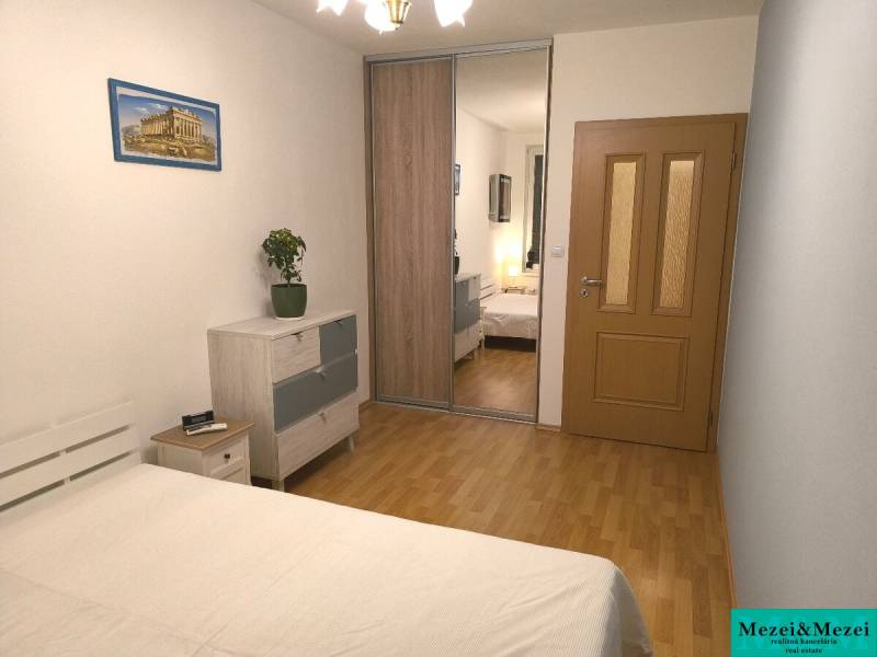 Schlafzimmer in einer 2-Zimmer-Wohnung mit Holzboden, Schränken mit Spiegel und Bild.