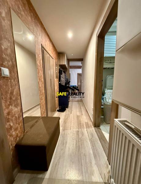 Flur in einer 2-Zimmer-Wohnung mit einem Boden in Holzoptik, einem Spiegel und einem Schuhschrank.