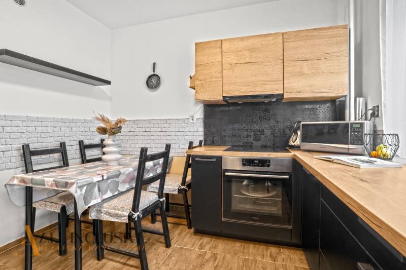 Eine Küche mit Holzdekor, Esstisch und Geräten in einer 3-Zimmer-Wohnung.