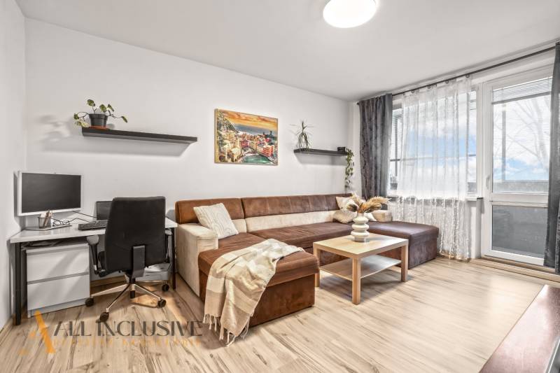 Wohnzimmer in einer 3-Zimmer-Wohnung mit Sofa, Schreibtisch und Boden in Holzoptik.