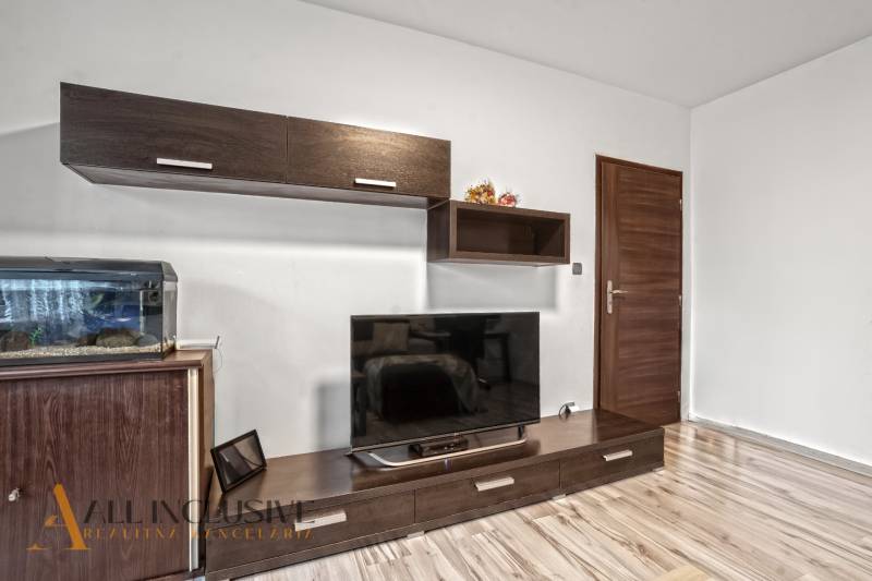 Wohnzimmer in einer 3-Zimmer-Wohnung mit Holzboden und großem Fernseher.