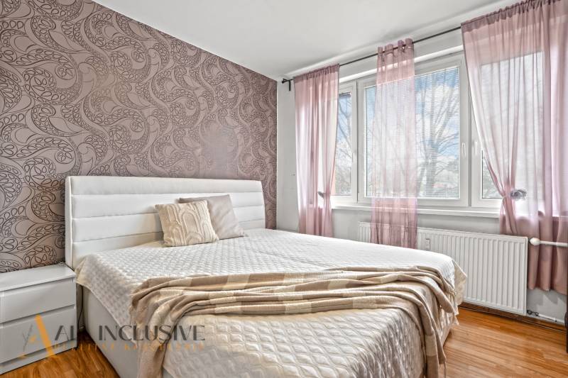 Schlafzimmer in einer 3-Zimmer-Wohnung mit dekorativer Tapete und Bodenbelag in Holzoptik.