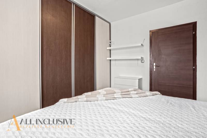 Schlafzimmer in einer 3-Zimmer-Wohnung mit Bett, Einbauschrank und minimalistischen Regalen.