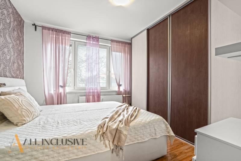 Schlafzimmer in einer 3-Zimmer-Wohnung mit Bett, Schrank und dekorativen Kissen, Boden mit Holzdekor.