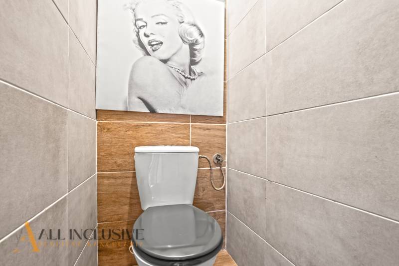 Toilette in einer 3-Zimmer-Wohnung mit Holzboden und einem Wandfoto.