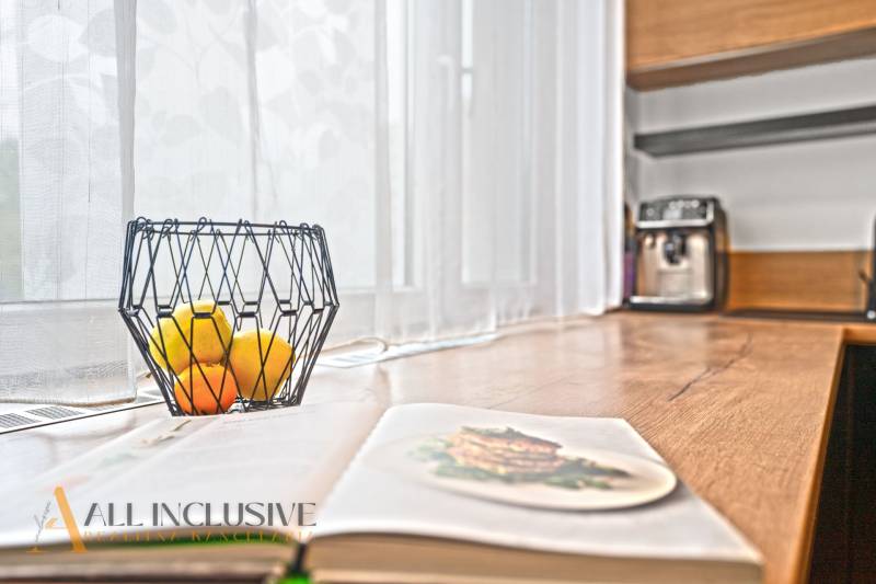 Offene Küche in einer 3-Zimmer-Wohnung mit Holzdekor, Obstschale auf dem Tisch.