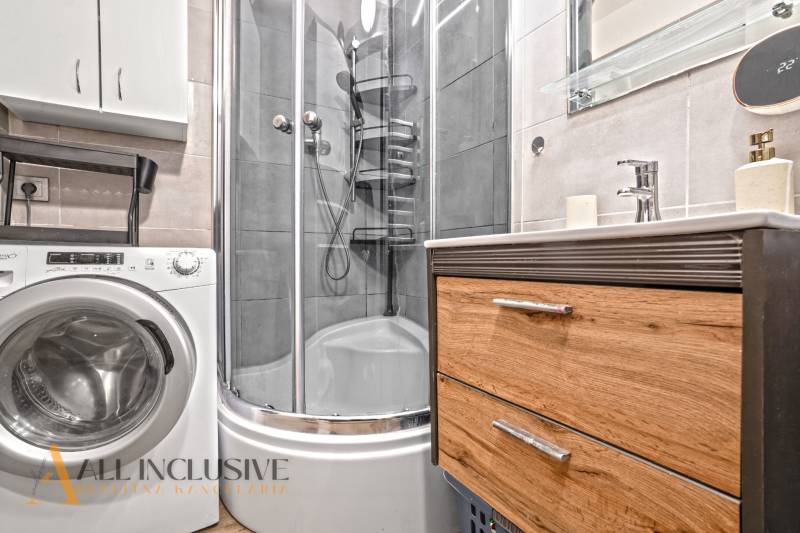 Badezimmer mit Waschmaschine, Duschkabine und Schrank in einer 3-Zimmer-Wohnung.