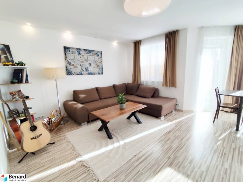 Wohnzimmer in einem Einfamilienhaus mit großem Sofa und Boden in Holzoptik.