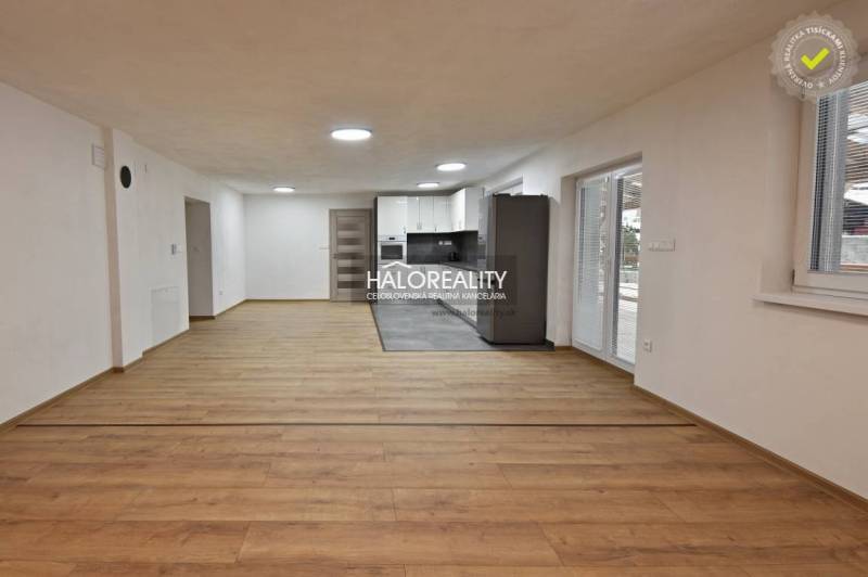 Wohnzimmer in einem Einfamilienhaus mit Küche, Holzboden, weiße Wände.