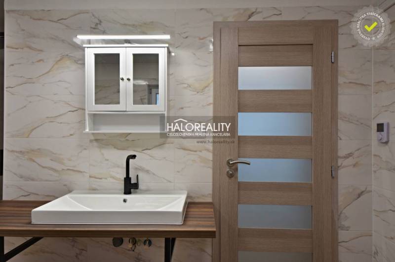 Badezimmer mit Waschbecken, schwarzem Wasserhahn und Schrank in einem Einfamilienhaus.